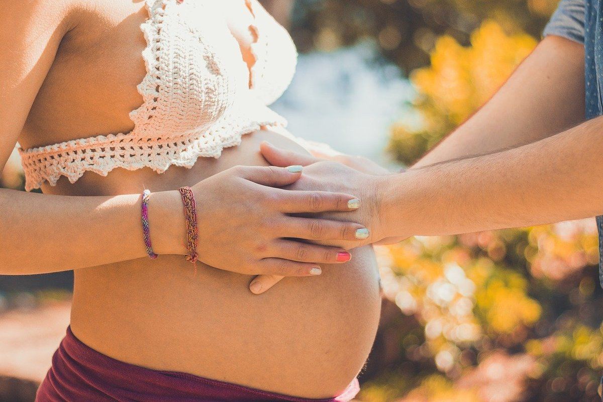 Sonhar com amiga próxima grávida: imagem de alguém colocando a mão na barriga de uma mulher grávida