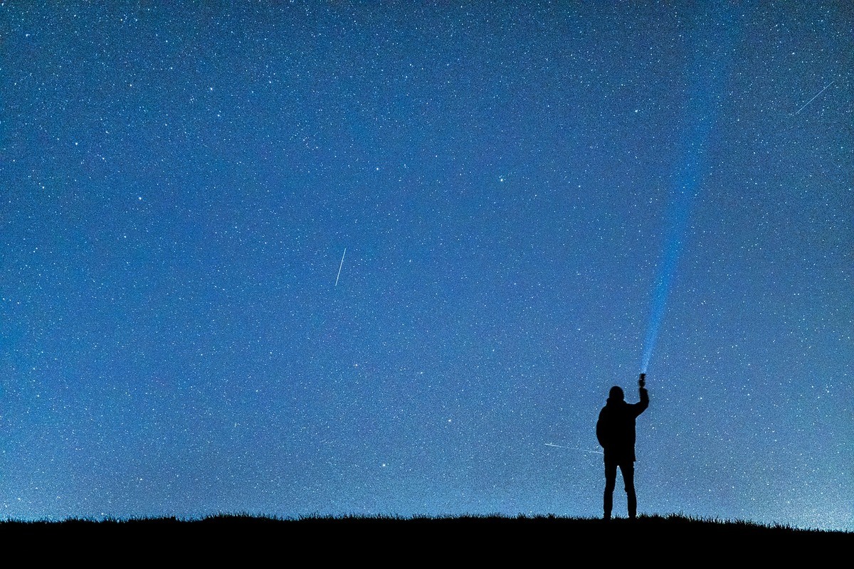 Sonhar que avista estrela cadente: imagem da silhueta de um homem vendo o céu com estrelas cadentes