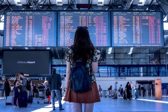 Menina tentando achar o voo no painel do aeroporto